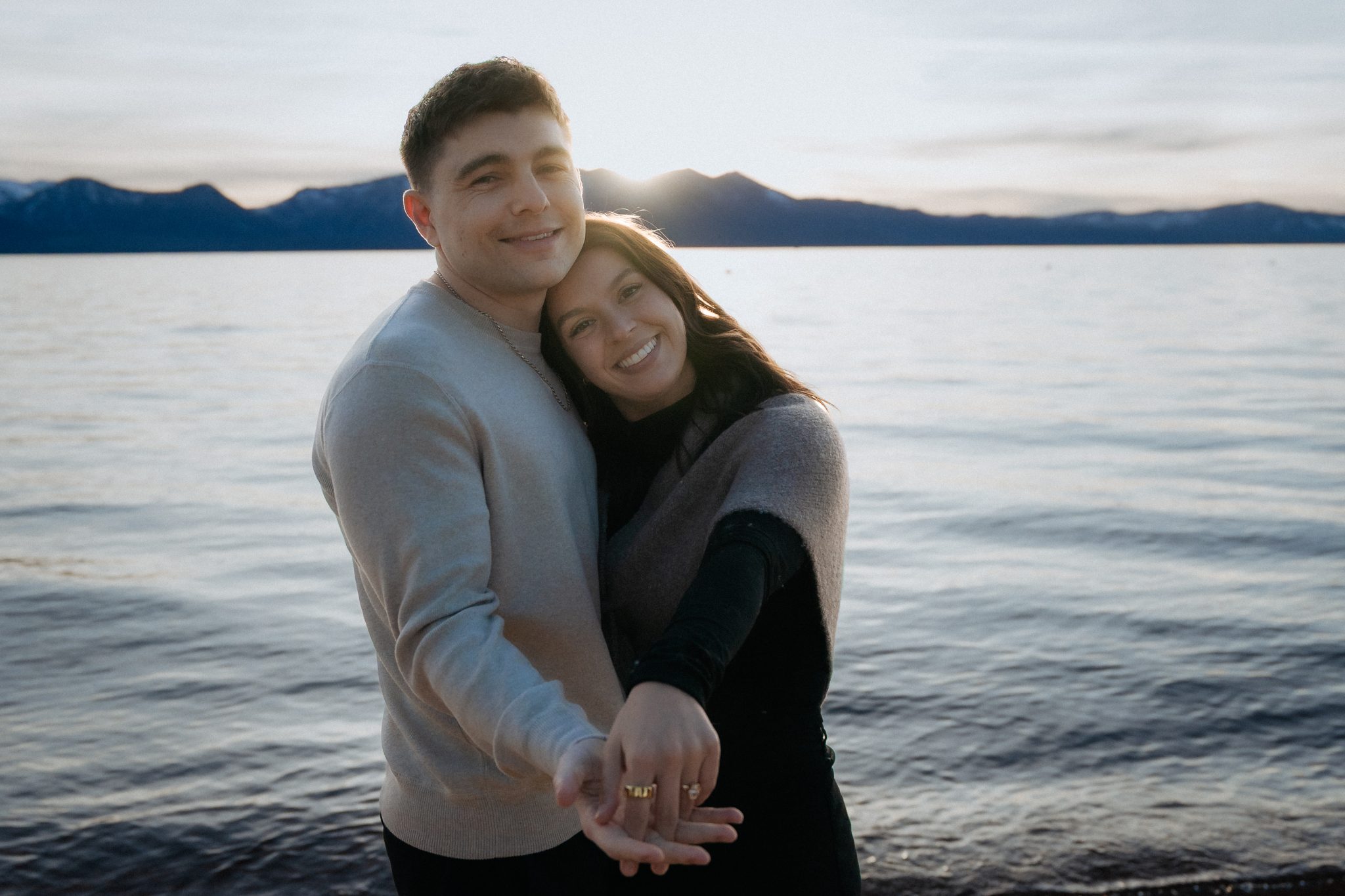 Edgewood Resort engagement photos of a happy couple holding hands by the Lake Tahoe shoreline at sunset.
