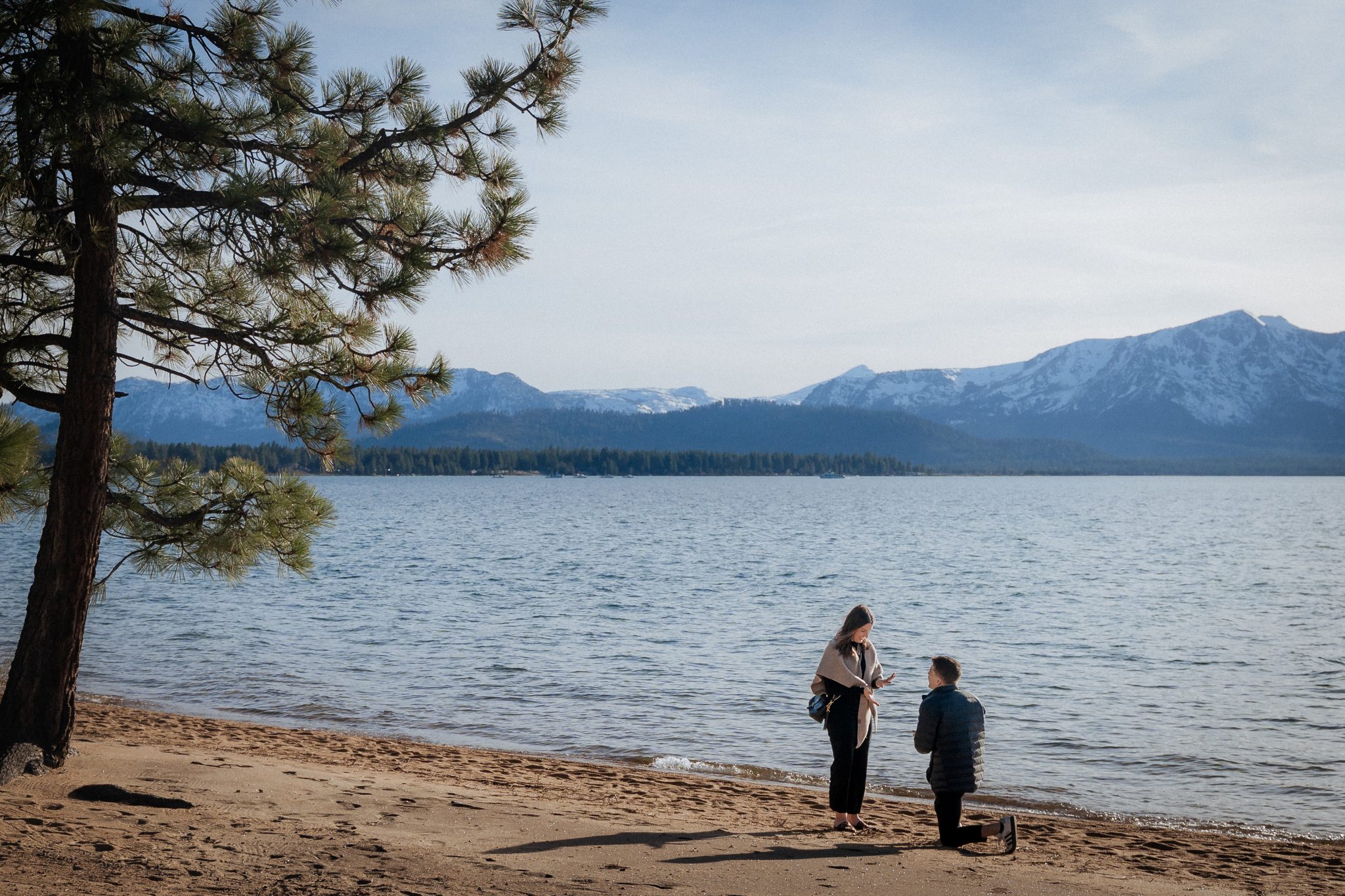 Edgewood Tahoe engagement photos capturing a surprise proposal on the Lake Tahoe shoreline with panoramic mountain views.