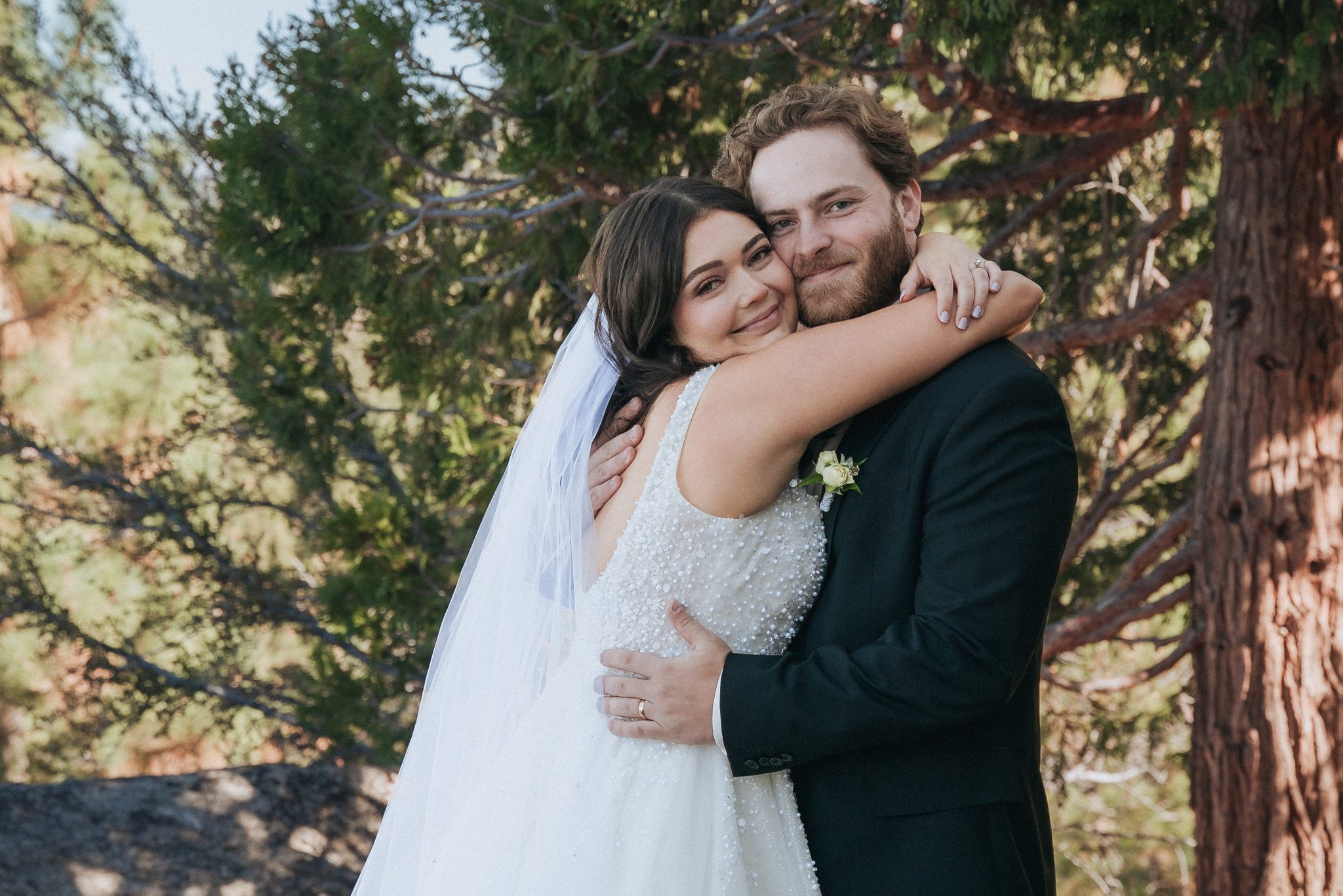 bride embracing groom beneath towering pine trees, demonstrating how to relax in front of the camera and create natural, authentic wedding photos in Lake Tahoe