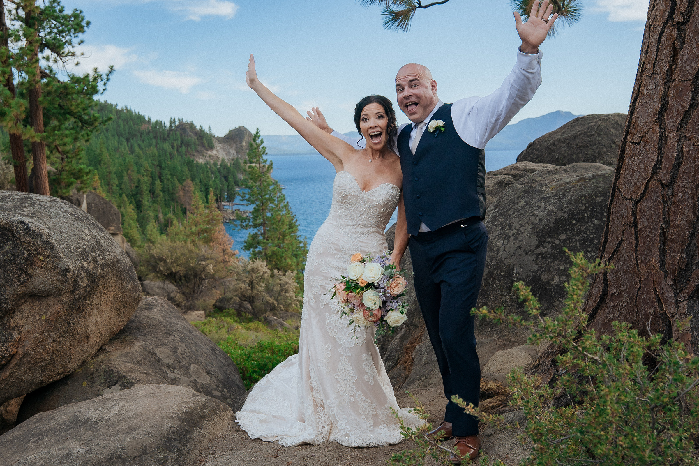 Logan Shoals elopement photography featuring a newlywed couple celebrating with raised arms against scenic Lake Tahoe mountain and rock views.