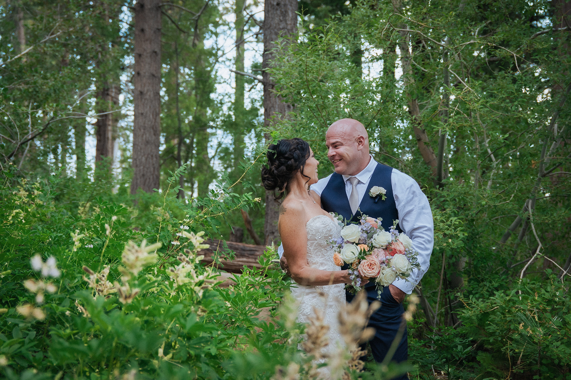 Logan Shoals intimate wedding portrait of a newlywed couple with a bouquet surrounded by lush trees and natural greenery.