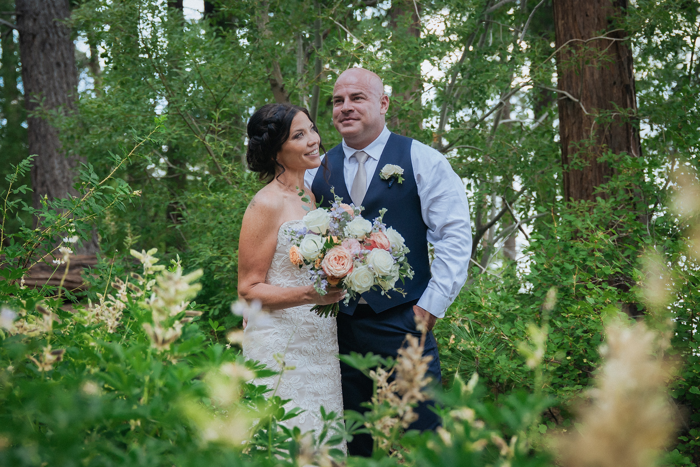 Logan Shoals intimate wedding portrait of a newlywed couple with a bouquet surrounded by lush trees and natural greenery.
