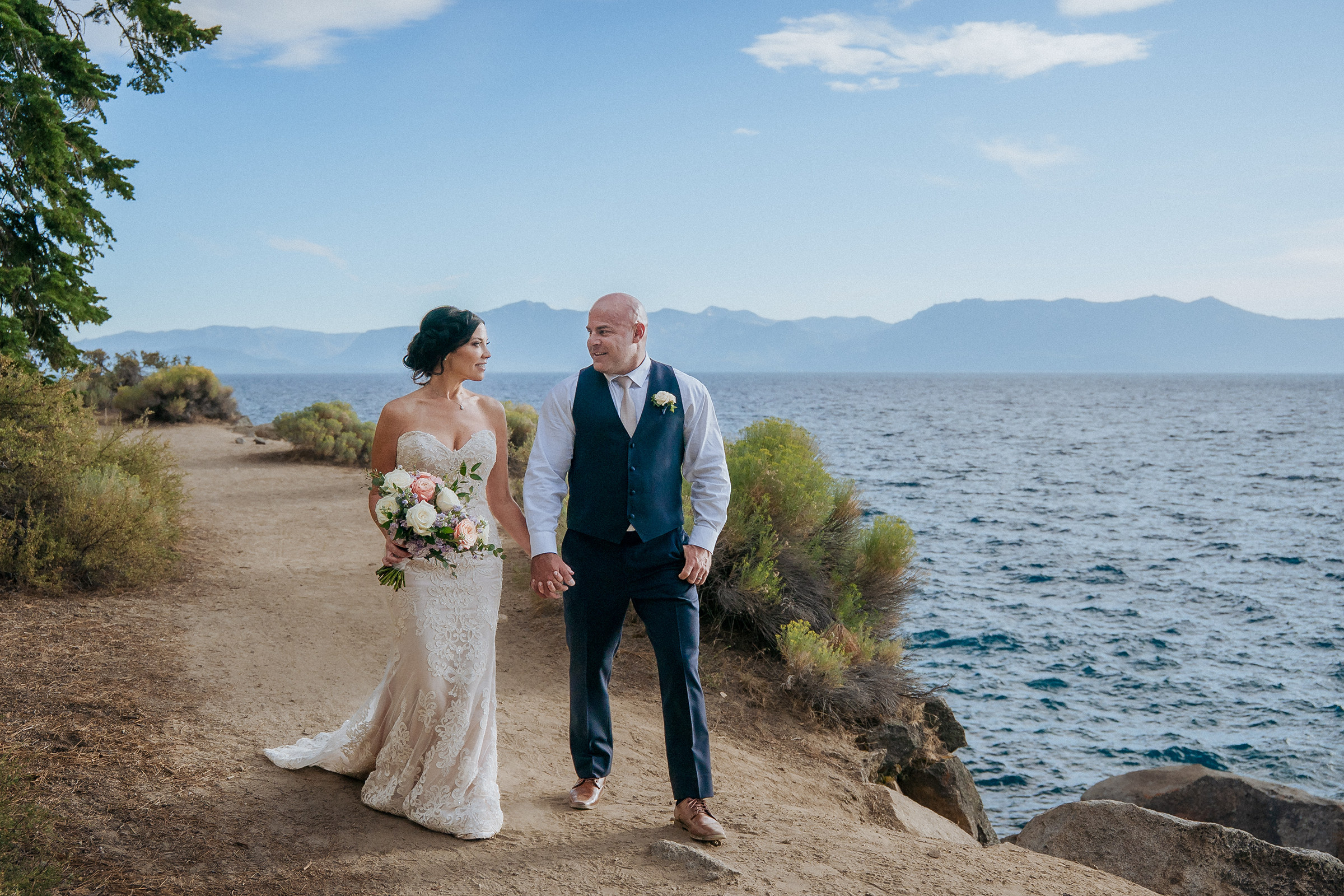 Logan Shoals Lake Tahoe elopement couple standing together along the scenic overlook with the lake and mountains in the background.
