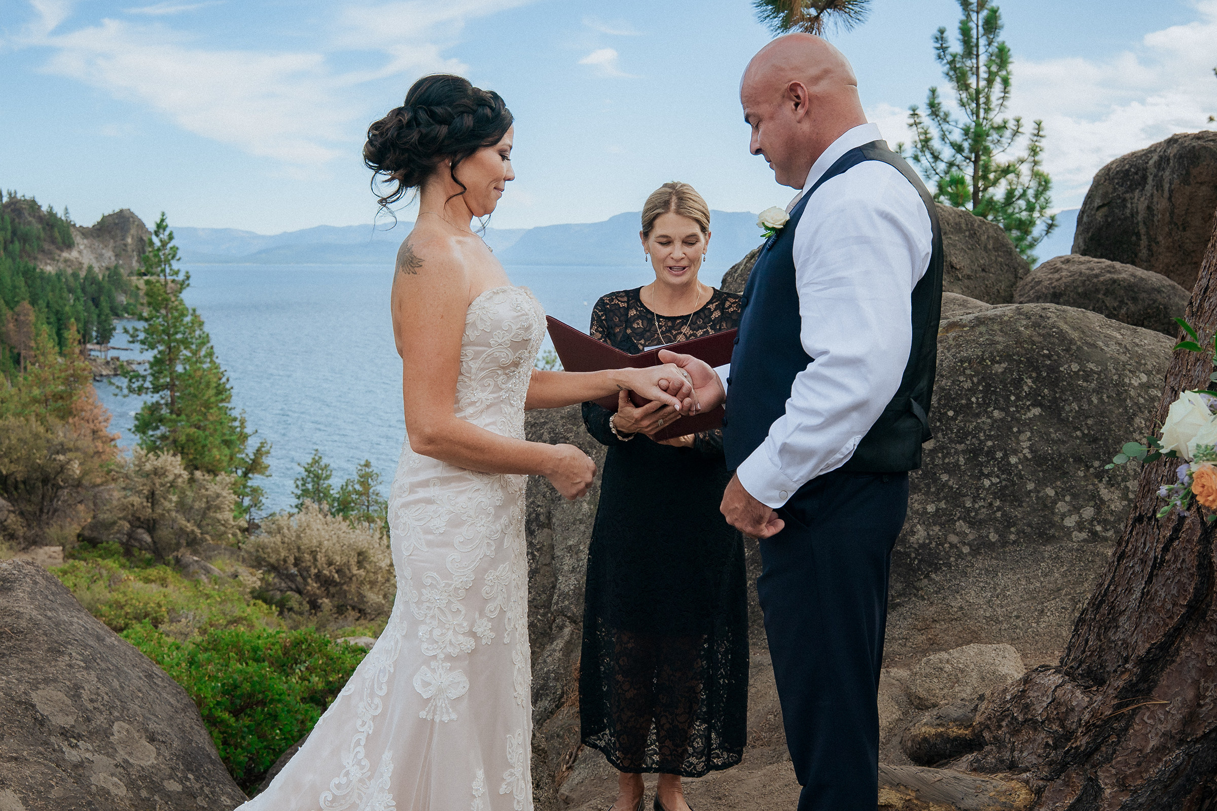 Logan Shoals Lake Tahoe wedding ceremony with a bride and groom exchanging vows with an officiant among scenic rocks overlooking the lake and mountains.