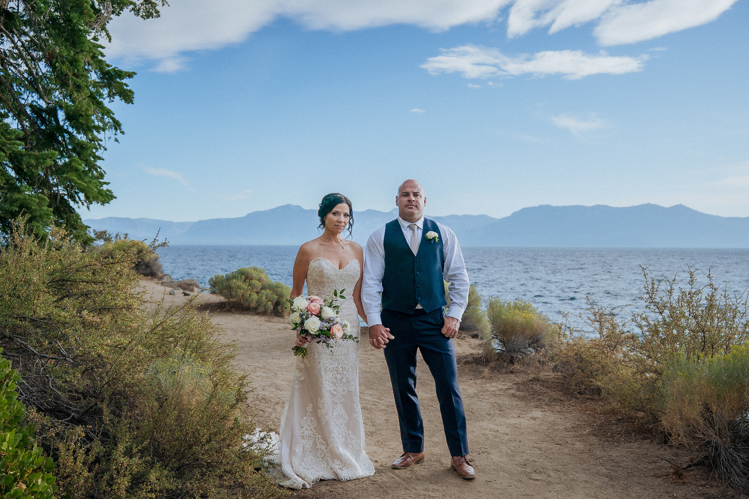 Logan Shoals wedding portraits of a newlywed couple standing together with a bouquet overlooking Lake Tahoe and scenic mountain views.